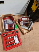 Overview of lot showing router bit case on floor and wooden crate with clamp components and precision square
