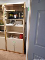 Full view of wood shelving unit showing open shelves, some contents inside, glass shelf on top, bottom wood doors, and missing glass door panel.