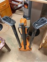 Full view of orange steel base with two vertical adjustable arms and pressure pads