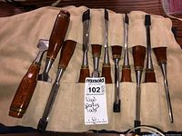 Eight wood chisels laid out in tan canvas roll