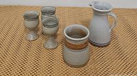Photo showing the complete set: 1 ceramic pitcher, 1 utensil crock, and 3 goblets on a woven textured surface