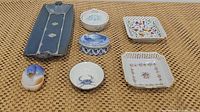 Full set of 7 decorative dishes and trays on woven surface, various colors and patterns visible