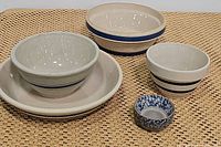All six bowls and ramekins arranged together on a woven surface to show size and style variations
