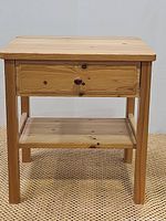 Front view of the natural wood nightstand showing drawer and open shelf below.
