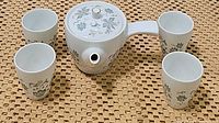 Top view of vintage Noritake porcelain teapot with lid and four matching floral cups arranged on woven surface.