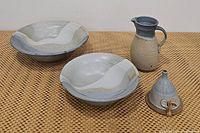 Stoneware pottery set on display including two bowls, a jug/pitcher, and a pottery funnel