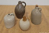 All four jugs grouped together on woven surface showing variety of colors and styles.
