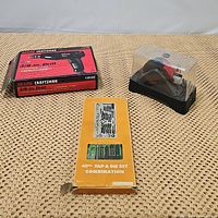 Three items displayed: Craftsman drill box on left, vintage tap & die set in center orange box, SKIL IXO2 cordless screwdriver in plastic case on right.