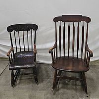 Photo of two rocking chairs side by side, showing the large wooden spindle back chair and the smaller black painted child's rocking chair with floral details.