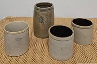 Four stoneware crocks placed on a woven surface showing overall set.