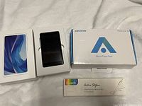 Photo of boxed AGPTEK music player, Aikove power bank box, and Evach stylus pen box together on white surface