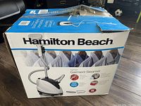 Front photo of the brand packaging box shows Hamilton Beach branding and a photo of the garment steamer device with a flexible hose and upright pole.