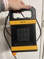 Front view of the Opolar space heater showing black mesh grille, yellow trim and handle for portability.