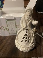 Photo showing white ceramic Santa Claus Scentsy warmer on wooden surface with original box in background.