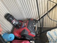 Full side view of Toro snow thrower showing red body, black chute, and metal handle.