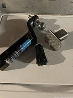 Photo of the towing items laid on a white surface showing the tow hitch, hitch cover, and converter plug.