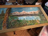 Full view of the painting showing the entire landscape and gold frame on a wooden floor.