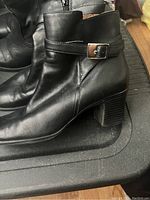 Side view of black leather women's ankle boot showing buckle and heel