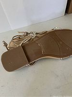 Close-up photo of the sole and straps of gold and silver roped Marc Fisher sandals showing wear on the sole and ankle buckle strap detail.