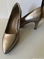 Side and angled view of the metallic gold Clarks pump showing the pointed toe, leather texture, and heel height.