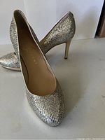 Close-up photo of front and side of the silver and gold textured pumps, showing Ivanka Trump branding inside.