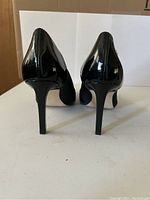 Photo showing rear view of black patent leather heels, 3.25 inch height, slim design.