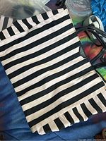 Black and white striped Victoria's Secret tote with black handles shown on dark background