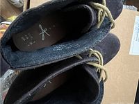 Top down view of black ankle boots showing insole marked with size and brand.