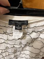 Close-up of label for black and white strapless jumpsuit showing Connected brand, size M, polyester fabric, made in USA