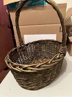 Single large wicker Easter basket shown upright with handle in natural woven material