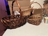 Four wicker baskets shown on a table; large dark brown basket in front with three other smaller baskets behind.