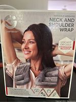 Photo of product box showing woman wearing gray SmartGear weighted neck and shoulder wrap. Highlights use for hot or cold therapy and relaxation benefits.