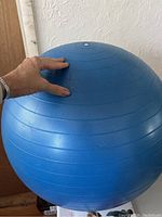 Blue Stability Swiss Ball with hand demonstrating size and smooth surface with minor wear.