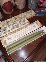 Three boxed Bayberry scented taper candles stacked with one open box showing two green taper candles.