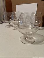 Six short wine goblets displayed on a white surface with a box in the background, showing overall size and shape.