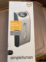 Box front of Simplehuman brushed stainless steel grocery bag holder showing product image and branding.