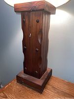Close-up of the wooden block base showing its weathered dark stained finish, metal bolts, and carved indentations on the wood surface.