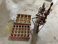 Wooden Coke and 7up bottle carriers, yellow Depression glass plates, spinning wheel, and oil lamp globe arranged on floor for overview