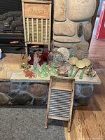 Full view of lot showing washboards, green ladles, glass items including candy dish, decanters, and decorative beads arranged on a stone hearth.