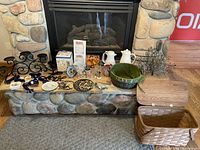 Full view of all lot items on a stone hearth including ceramic, metal and basket items.