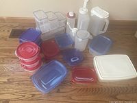 Overview of various plastic food storage containers of multiple sizes, shapes, and colors, placed on a wooden surface.