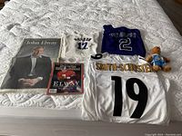 Photo of all memorabilia items laid out including jerseys, signed baseballs, Sports Illustrated magazine, and newspaper insert.