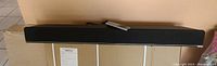 Front view of the Vizio sound bar showing its black fabric grille and included remote control.