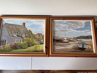 Both oil paintings showing an English countryside house and a seaside harbor with boats, framed in wooden frames.