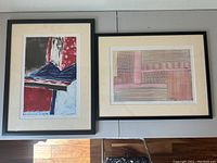 Two framed monoprints by Mary Nissen shown side by side hanging on a wall, one titled 'Flag' with bold geometric colors and shapes, and the other with linear abstract patterns in muted colors.