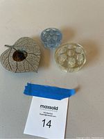 Three flower arrangement frogs including a pewter leaf with metal pins and two round glass frogs (blue and clear)