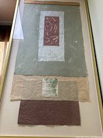 Front view of framed mixed media paper collage art by David Kimball showing layered papers and abstract shapes in green, white, beige, and brown tones.