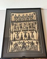 Framed tapestry shown fully hung on a wall, displaying the overall piece including the black frame and glass.