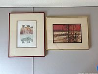 Two framed lithographs hung side by side on wall, one with a red frame and the other gold frame.