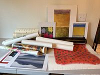 Overview of unframed art reproductions and rolled posters on table